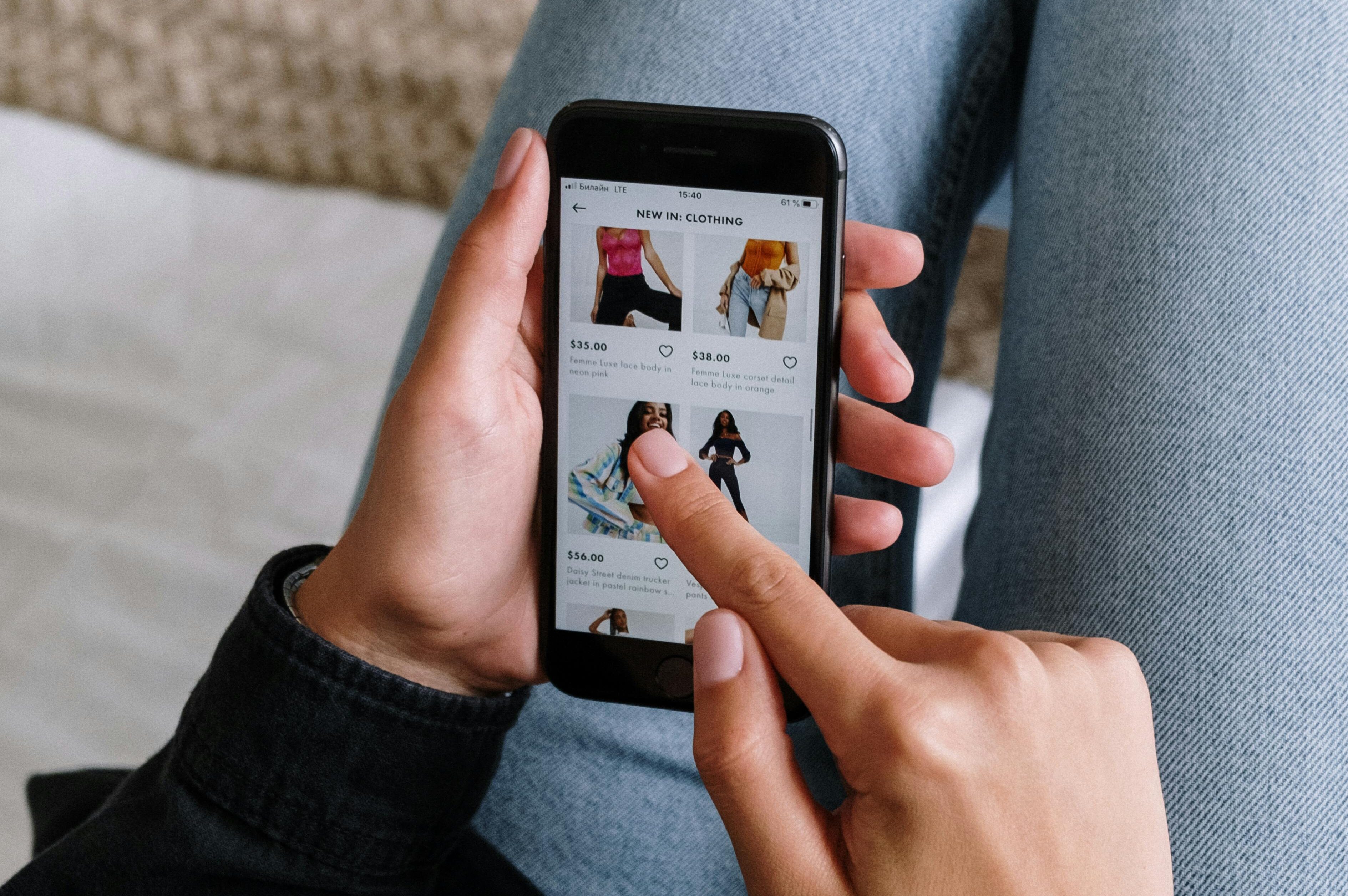 Person shopping online for clothes on their phone. Post-purchase email examples.