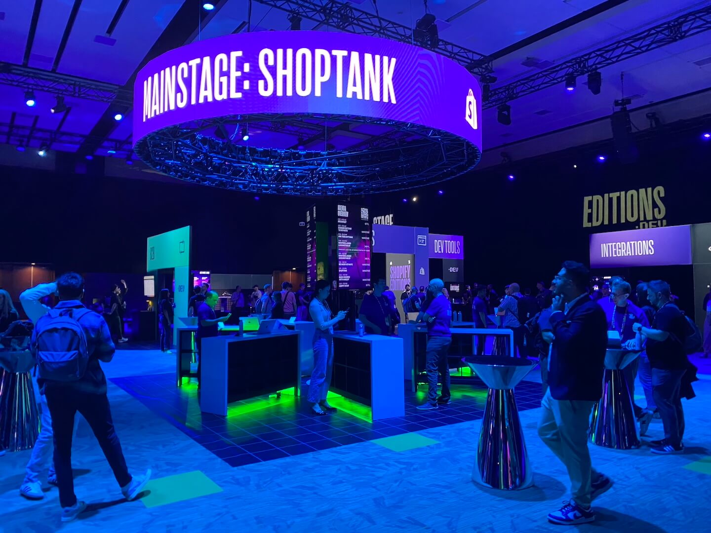Conference booth with "MAINSTAGE: SHOPTANK" sign and people. Relevant for eCommerce agency events.