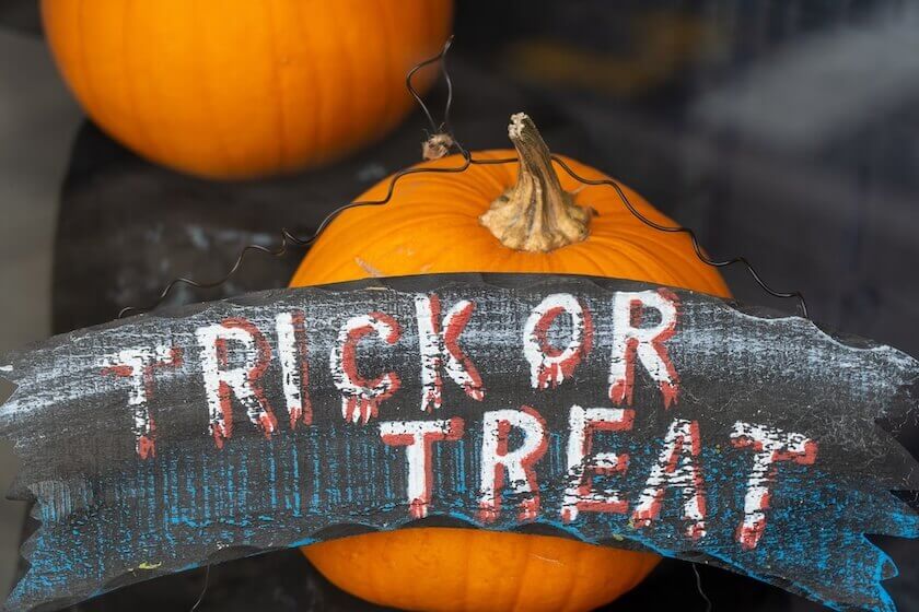 Halloween sign with pumpkins reading "TRICK OR TREAT" on black background